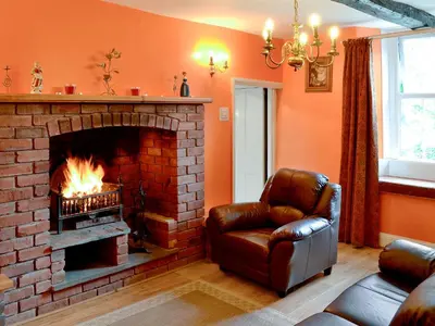 a living room with a brick fireplace and a leather chair at Foldgate in Waberthwaite