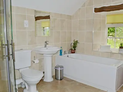 a bathroom with a toilet and a tub and a sink at Whistling Green in Ulpha