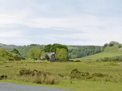 a house in the middle of a green field at Whistling Green in Ulpha