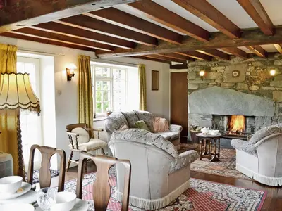 a living room with couches and a stone fireplace at Whistling Green in Ulpha