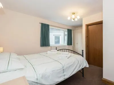 a bedroom with a large white bed with a window at Oaklands in Langrigg
