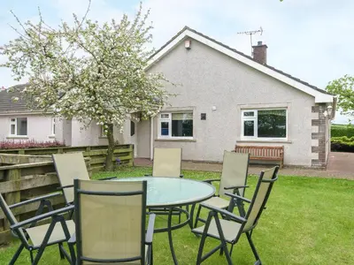 a table and chairs in front of a house at Oaklands in Langrigg