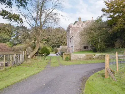 an old stone house with a fence and a road at Whitehall Pele Tower in Mealsgate