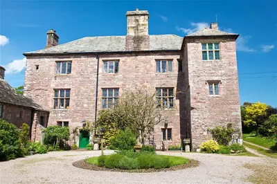 an old stone building with a green door in front of it at Johnby Hall in Penrith