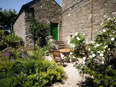 a garden with a bench and a green door at Johnby Hall in Penrith