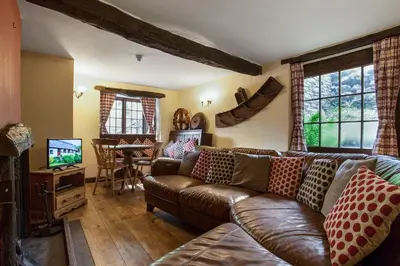 a living room with a leather couch and a television at The Coppermines Mountain Cottages - Carpenters, Millrace, Pelton Wheel, Sleeps 14 in Coniston