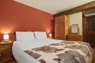 a bedroom with a bed and two lamps and a mirror at The Coppermines Mountain Cottages - Sawyers, Carpenters, Millrace, Sleeps 18 in Coniston