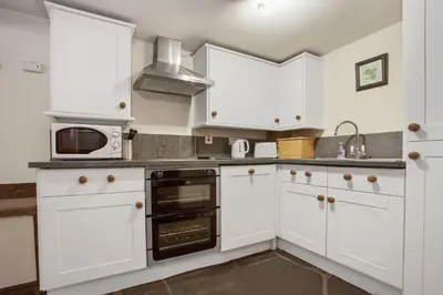 a kitchen with white cabinets and a microwave at The Coppermines Mountain Cottages - Sawyers, Carpenters, Millrace, Sleeps 18 in Coniston