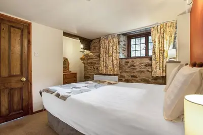 a bedroom with a large white bed and a window at The Coppermines Mountain Cottages - Sawyers, Carpenters, Pelton Wheel, Sleeps 18 in Coniston