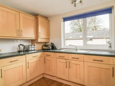 a kitchen with wooden cabinets and a window at Whitbarrow 24 in Penrith