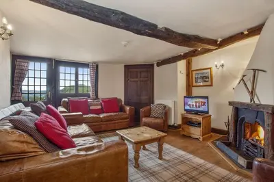 a living room with a couch and a fireplace at The Coppermines Mountain Cottages - Sawyers, Millrace, Pelton Wheel, Sleeps 16 in Coniston