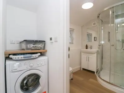 a washing machine in a bathroom with a shower at Dalegarth Hall Farm Cottage 2 in Holmrook