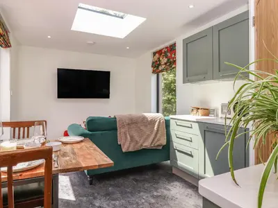 a kitchen and living room with a green couch at Brow Wood Cabin in Penrith