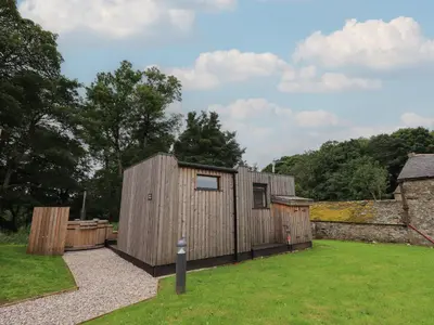 a small wooden building in a yard next to a building at Brow Wood Cabin in Penrith