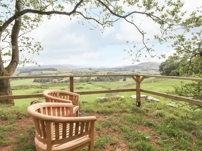 two chairs sitting on a porch looking out over the hills at Brow Wood Cabin in Penrith