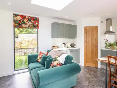 a living room with a blue couch and a kitchen at Brow Wood Cabin in Penrith