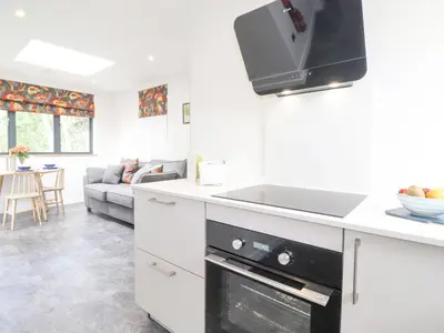 a white kitchen with a sink and a stove top oven at Bluebell Cabin in Penrith