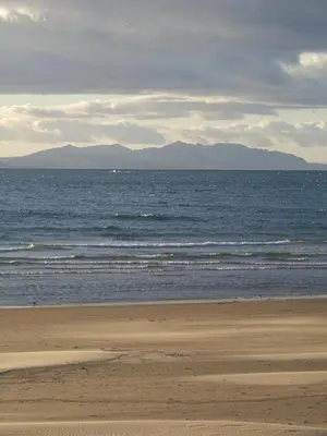 a beach with the ocean and mountains in the background at Horizon Hotel in Ayr