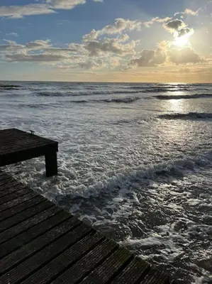 a view of the ocean from a wooden pier at Lake District Coastal cottage in Seascale