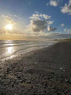 a beach with the sun shining on the water at Lake District Coastal cottage in Seascale
