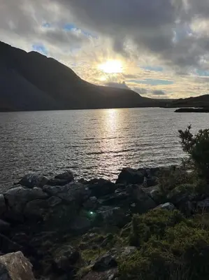 a sunset over a large body of water with mountains at Lake District Coastal cottage in Seascale