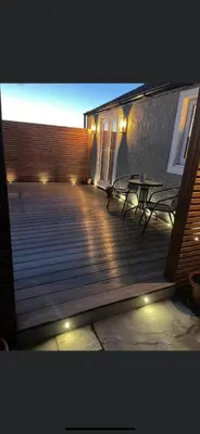 a deck with two benches and a building with lights at Lake District Coastal cottage in Seascale