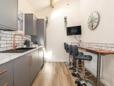 a kitchen with a counter and a bar with stools at The Granary in Wigton