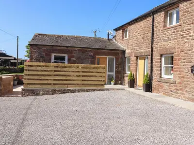 a brick house with a wooden fence in front of it at The Granary in Wigton