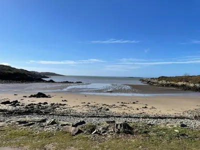 a beach with rocks and the ocean on a sunny day at The Vital Spark in Gatehouse of Fleet