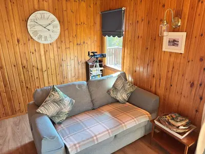 a living room with a couch and a clock on the wall at The Vital Spark in Gatehouse of Fleet