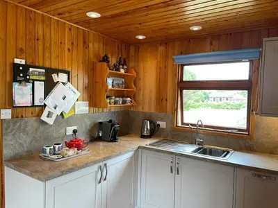 a kitchen with white cabinets and a sink and a window at The Vital Spark in Gatehouse of Fleet