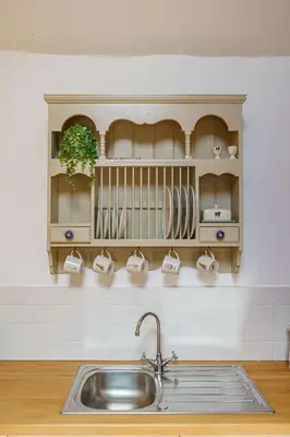 a kitchen with a sink and a shelf with cups at The Haybarn in Dundrennan
