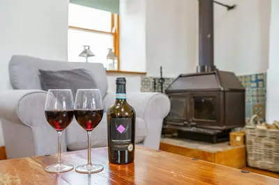 two wine glasses on a wooden table with a bottle of wine at The Haybarn in Dundrennan