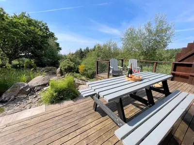 a wooden deck with a picnic table and benches at Beautiful 2BR Beach Lodge Set In Stunning Gardens - Pass the Keys in Dalbeattie