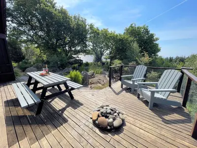 a wooden deck with two benches and a table and a dog at Beautiful 2BR Beach Lodge Set In Stunning Gardens - Pass the Keys in Dalbeattie