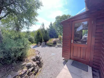 a large wooden door on a building with a garden at Beautiful 2BR Beach Lodge Set In Stunning Gardens - Pass the Keys in Dalbeattie