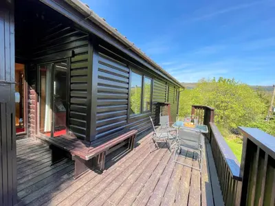 a black tiny house with a table and chairs on a deck at Beautiful Golf and Beach Lodge in Stunning Location - Pass the Keys in Dalbeattie