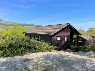 a small wooden house with a roof at Beautiful Golf and Beach Lodge in Stunning Location - Pass the Keys in Dalbeattie