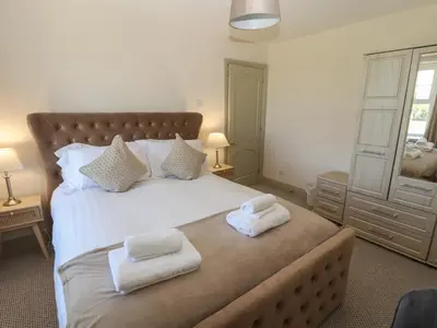 a bedroom with a large bed with towels on it at Rose Bank Cottage in Carlisle