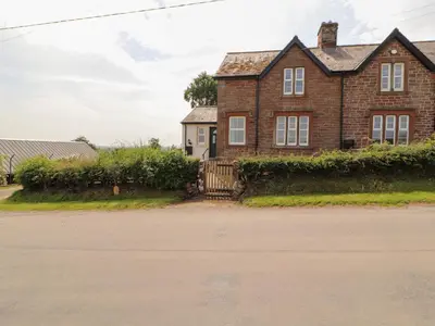 a brick house with a gate in front of it at Rose Bank Cottage in Carlisle