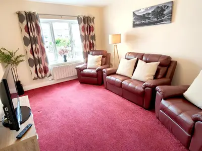 a living room with two leather chairs and a red carpet at The Paddock in Keswick