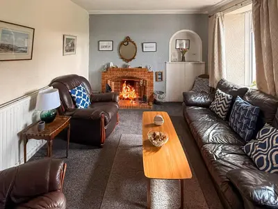 a living room with leather furniture and a fireplace at Kilpatrick Farm House in Pinmore