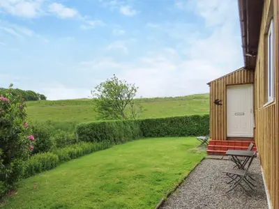 a house with a grass yard next to a building at Swallow Lodge in Carsphairn