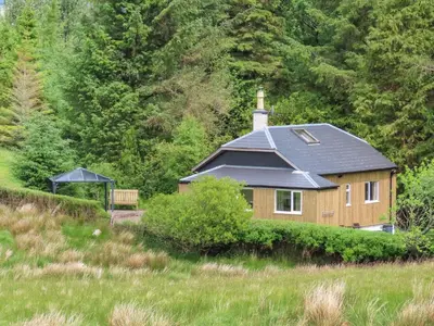 a house with a black roof in a field at Swallow Lodge in Carsphairn