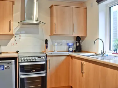 a kitchen with wooden cabinets and a stove top oven at Burnbank in Kirkgunzeon