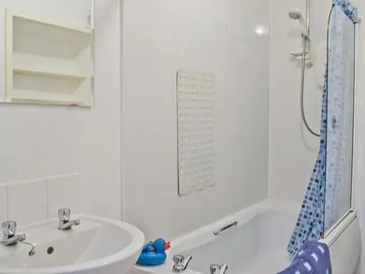 a white bathroom with a sink and a bath tub at Burnbank in Kirkgunzeon