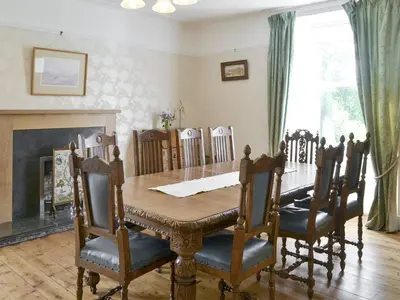 a dining room with a table and chairs and a fireplace at Burnfoot Of Cluden in Holywood