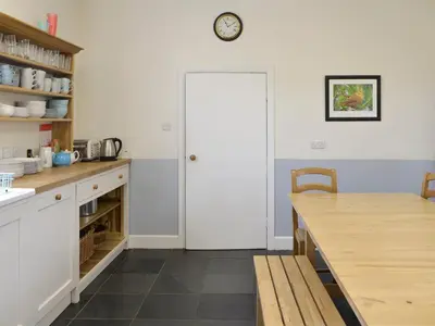 a kitchen with a table and a clock on the wall at Burnfoot Of Cluden in Holywood