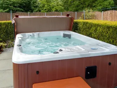 a jacuzzi tub with a bench in a backyard at Blaeberry Cottage - 28061 in Dinwoodie Mains