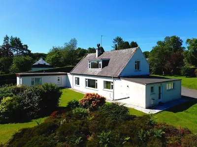 a white house with a gray roof on a green field at Mountain Cross in Gatehouse of Fleet